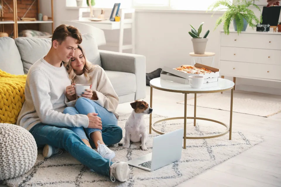 A couple reviewing health coverage on a laptop at home with their dog