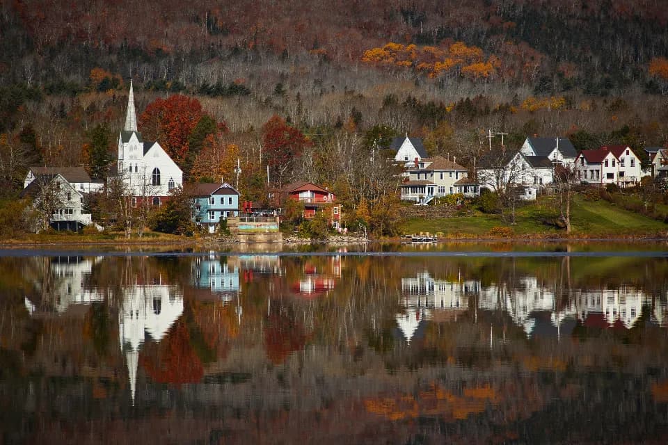 A small-town church and autumn trees reflected in still water